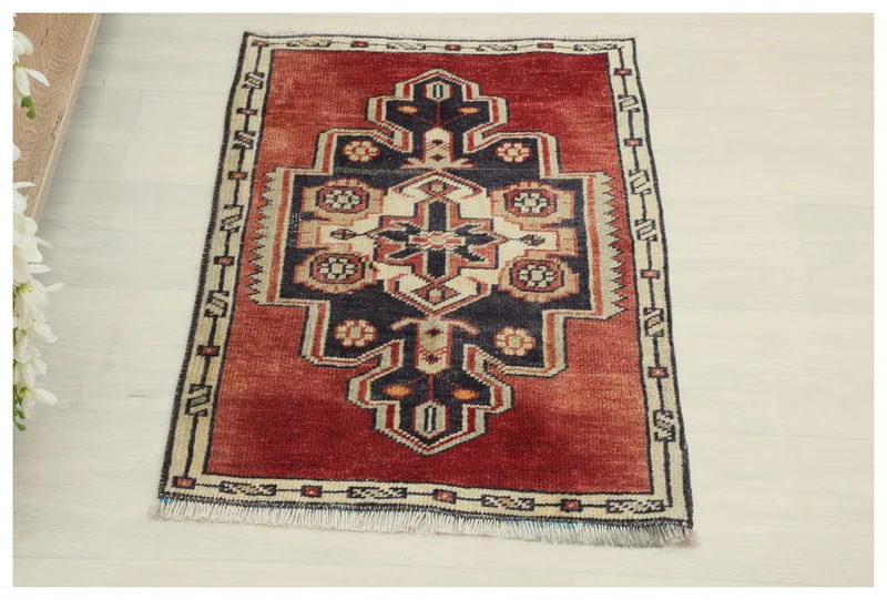 Full top view of the vintage red, navy, and ivory geometric medallion rug on a white floor.