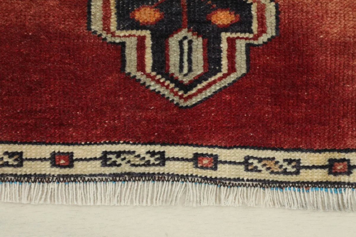 Close-up detail of the rug's border and fringe, highlighting the ivory and navy geometric patterns.
