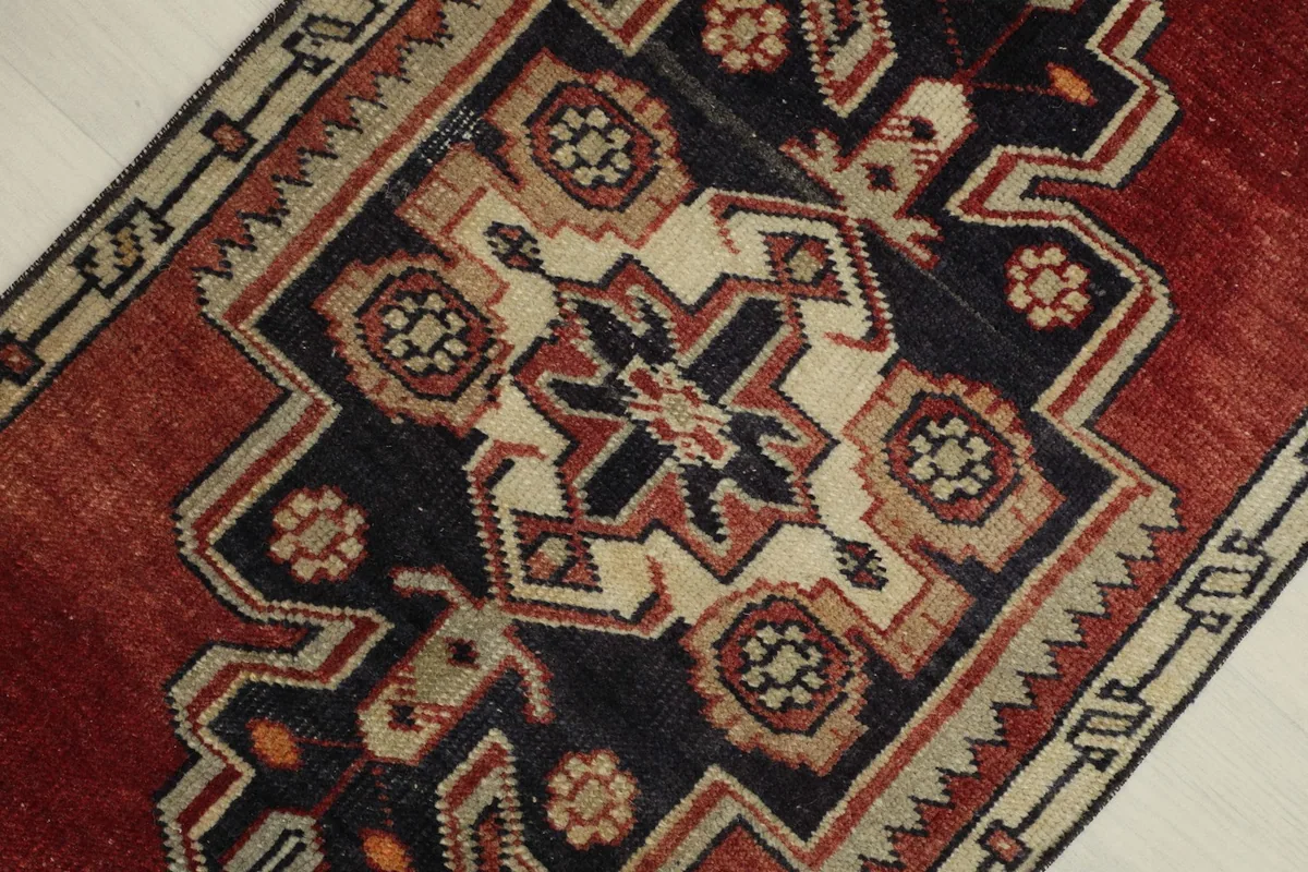 Overhead close-up of the rug's central geometric medallion, showing the navy, ivory, and red wool fibers.