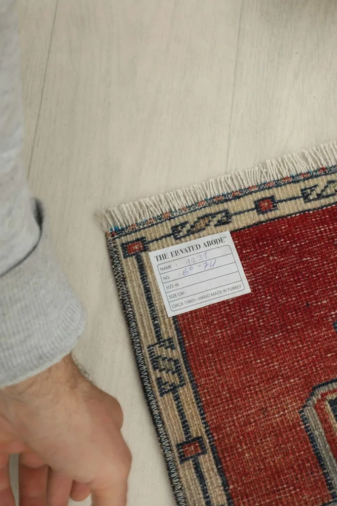 Close-up of the rug's back, displaying the hand-knotted construction and a tag from the cleaning service.