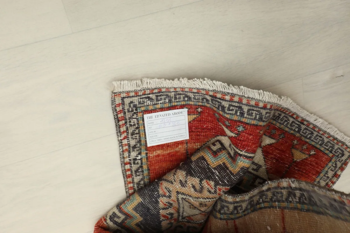 Overhead view of the rug with a label attached, showing the back of the hand-knotted construction