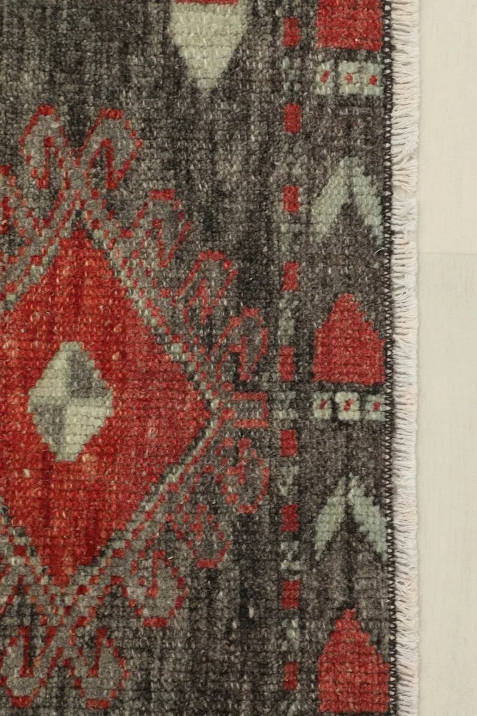 Close-up detail of the rug's red geometric motif and charcoal background