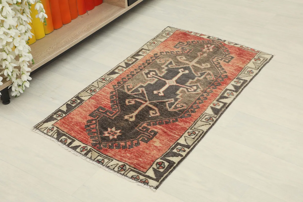 Angled view of the rust and black geometric rug in a home setting near a shelf