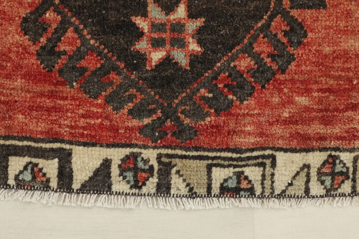 Close-up detail of the central black geometric motif and surrounding rust field with fringe