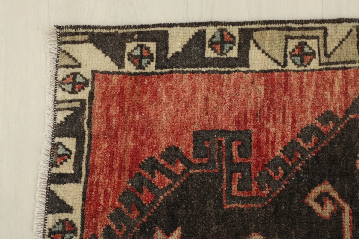 Corner detail showing the beige and black geometric border pattern of the rug