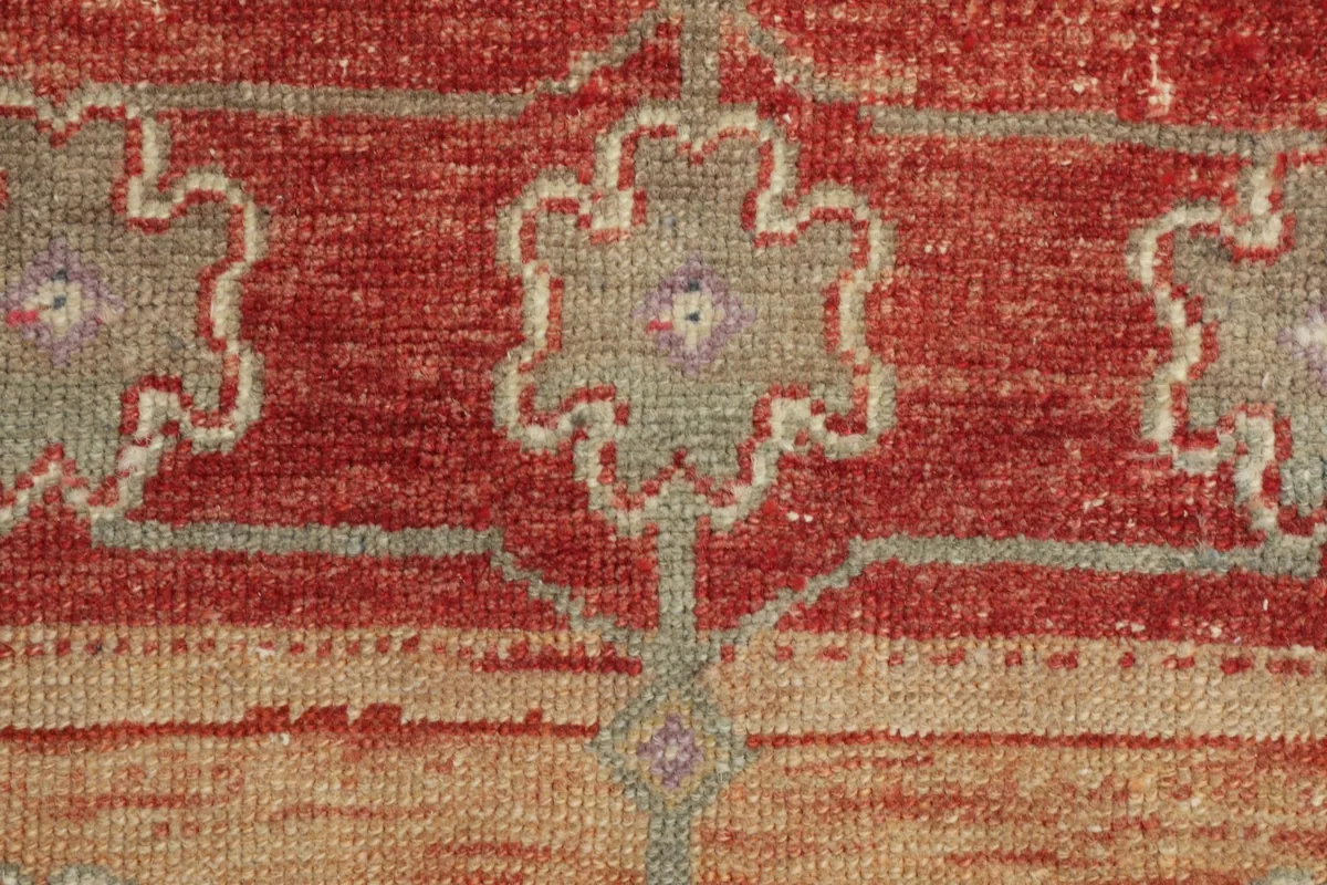 Detailed view of one of the gray floral-geometric motifs against the red field, showing texture.