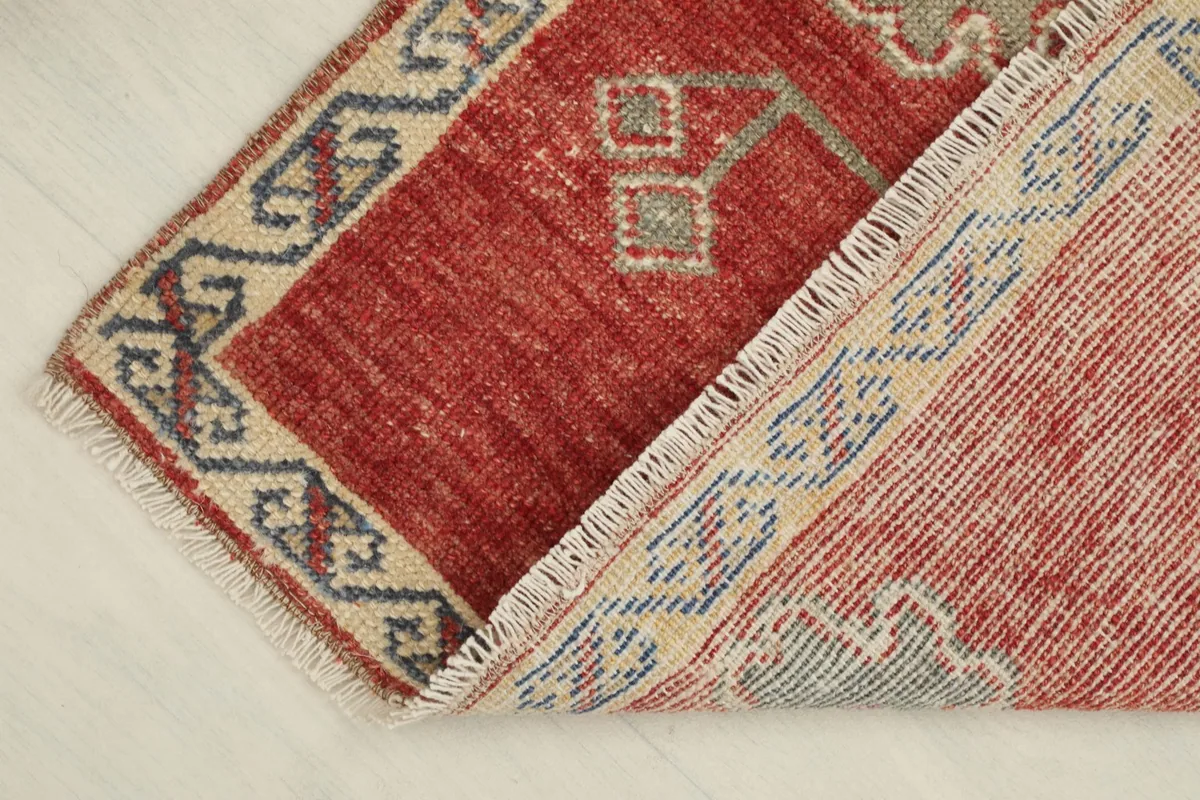 The rug partially folded to reveal the hand-knotted wool pile and the cotton foundation on the reverse side.