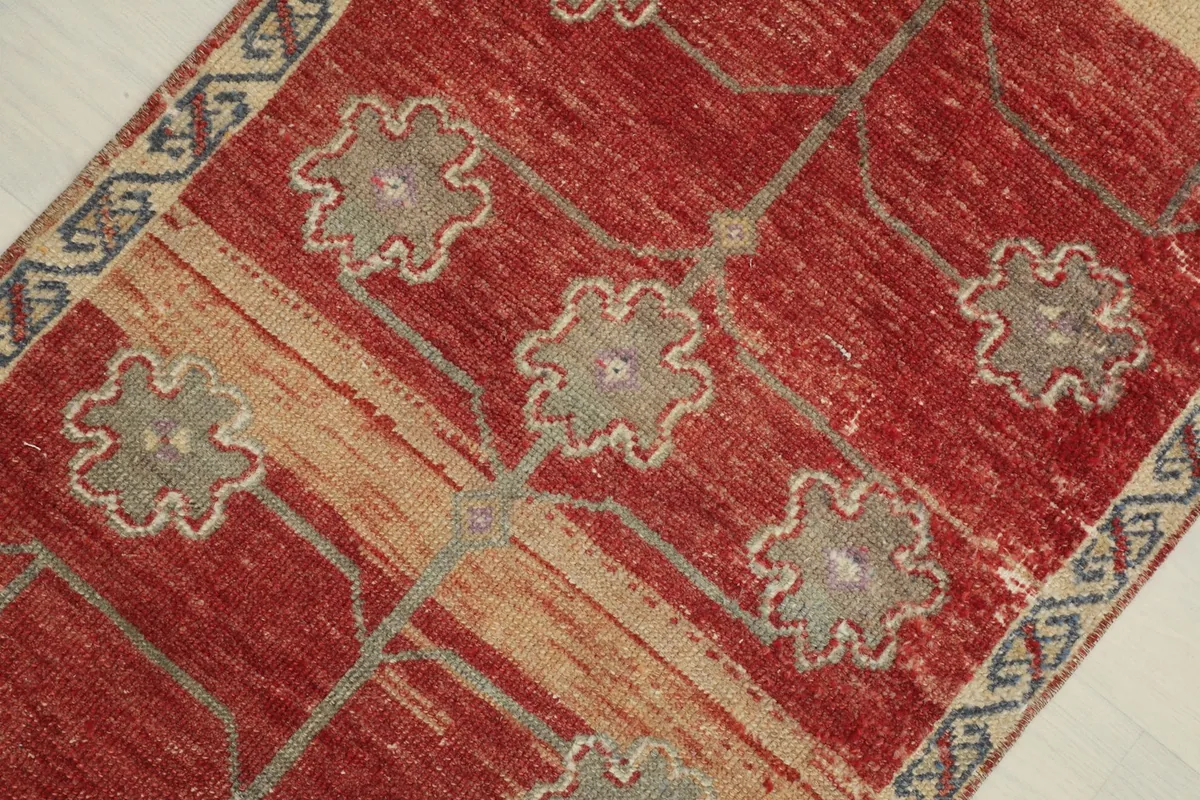 Overhead view focusing on the central tree-like motif and the varied red and beige tones in the rug.