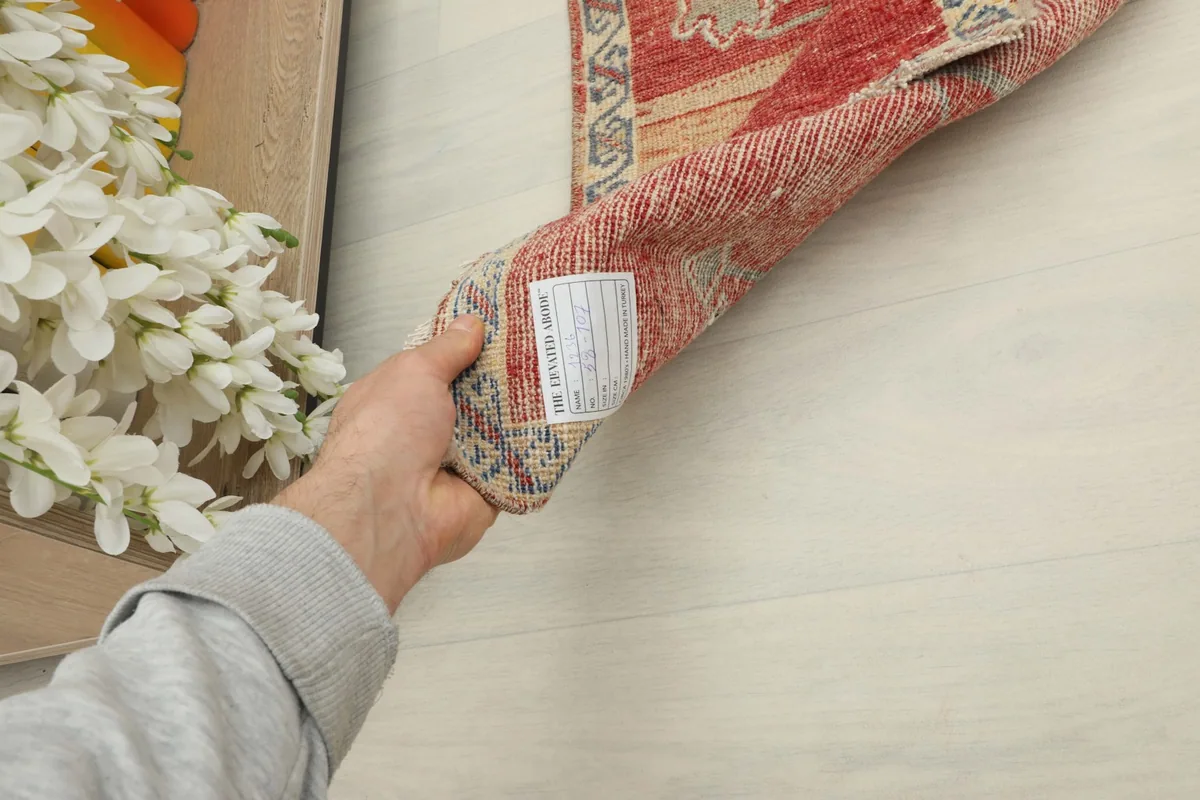 A hand holding the rolled rug, illustrating its manageable size and thickness.