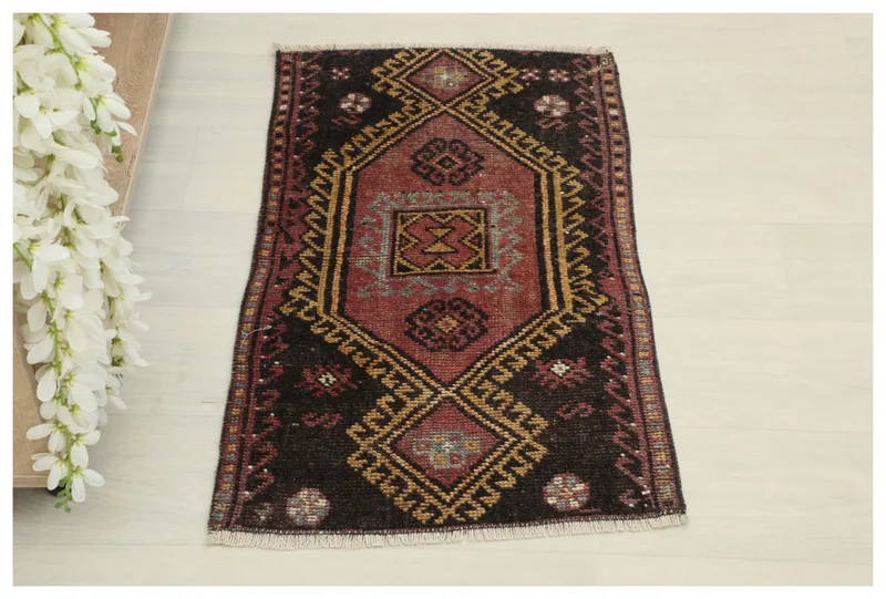 Overhead view of the 1'7" x 2'9" vintage Anatolian rug with a dark red field and geometric patterns.