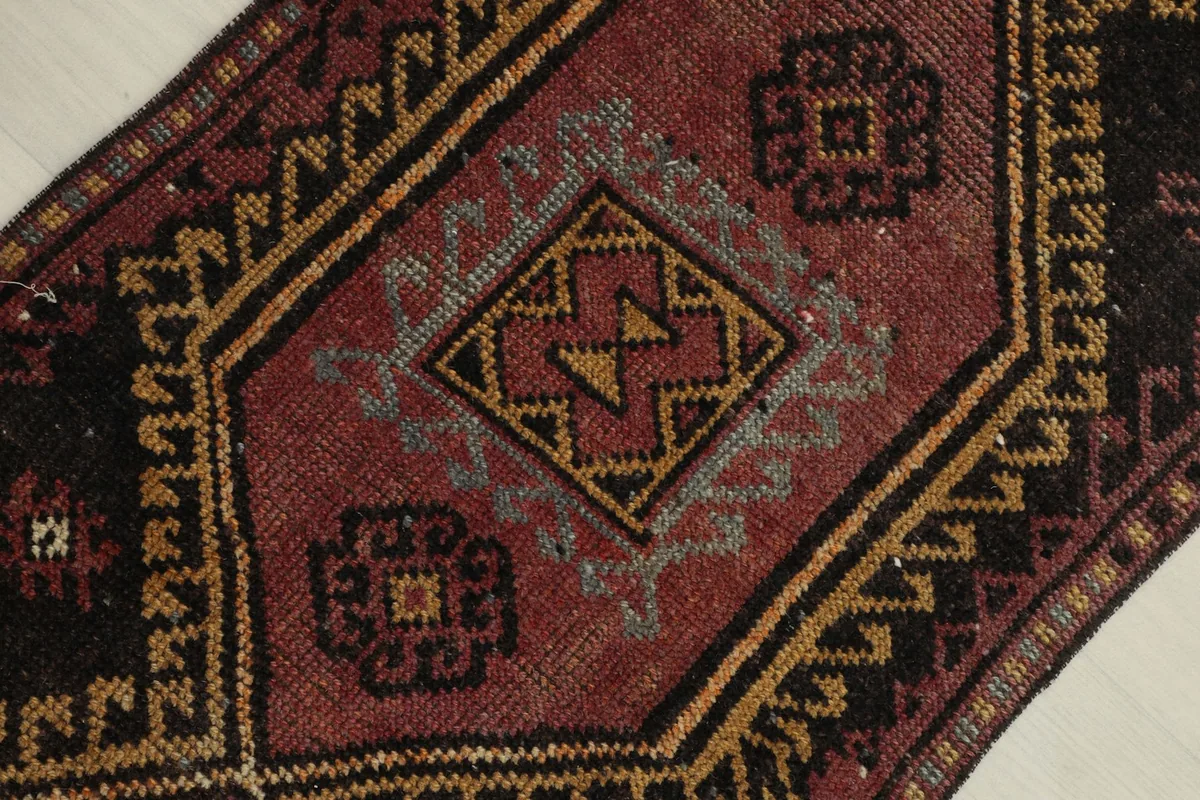 Detailed view of the central medallion and surrounding geometric motifs in red, gold, and gray.