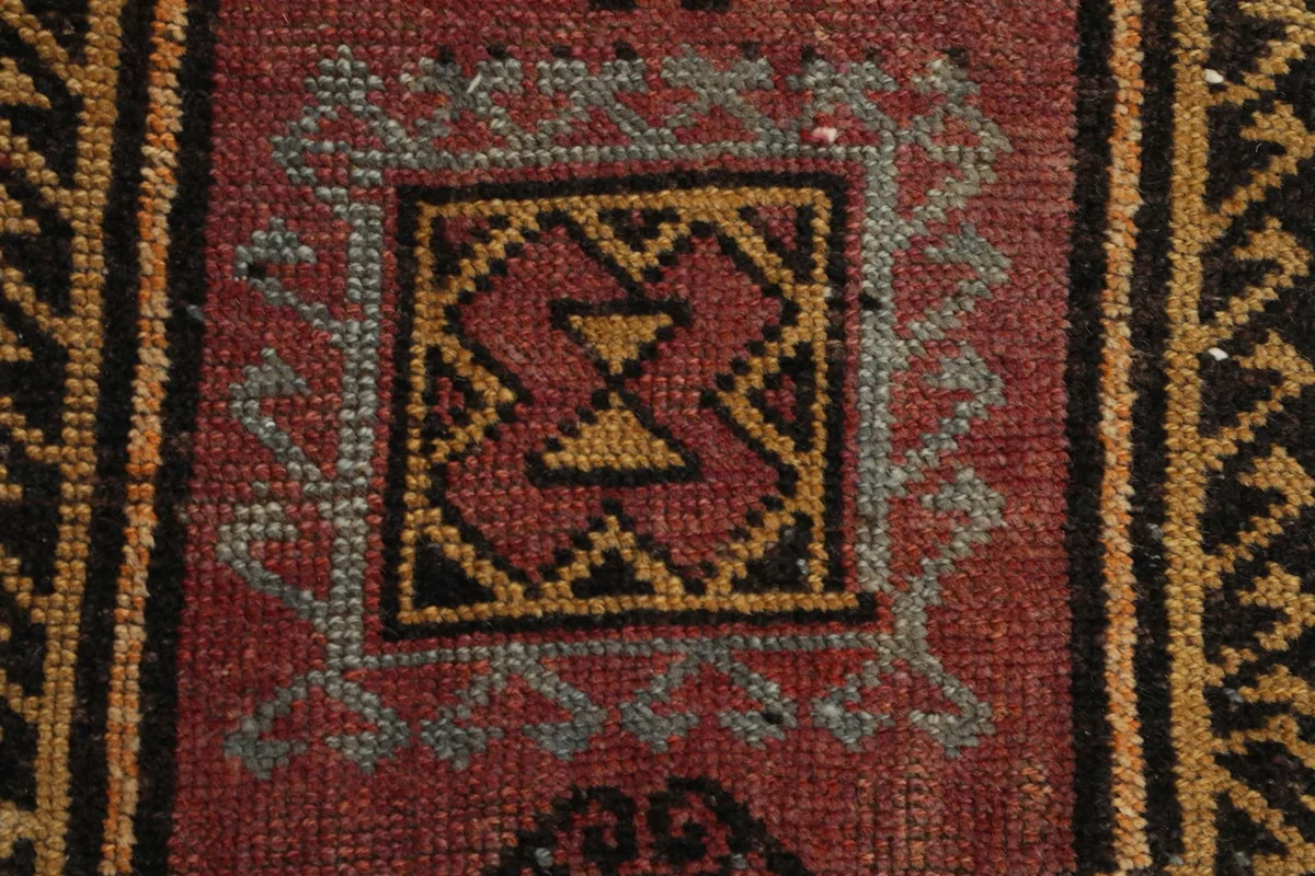 Close-up of the central geometric motif within the red field, highlighting the intricate knotting.
