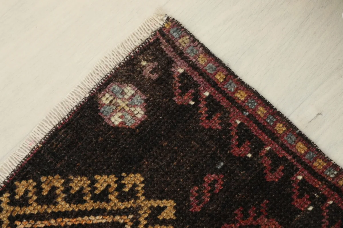 Close-up of the rug's upper corner, revealing the muted colors and hand-knotted craftsmanship.