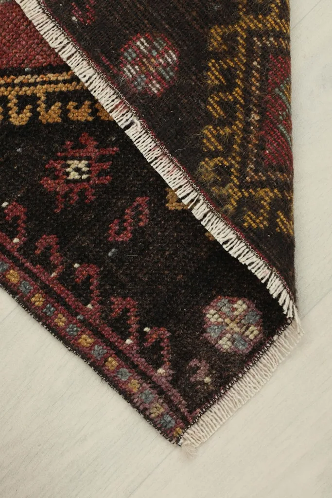 View of the rug folded to show its flexibility and the back of the hand-knotted construction.