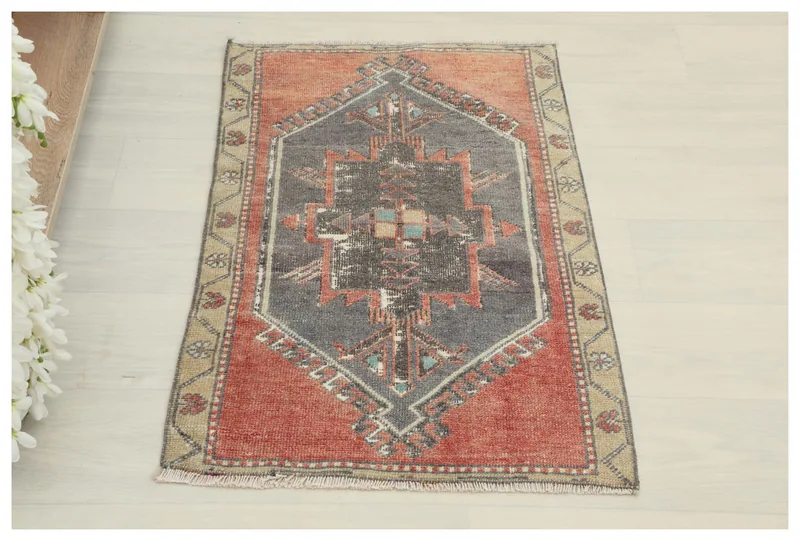 Full top view of the red and charcoal geometric vintage Anatolian doormat on a white background.
