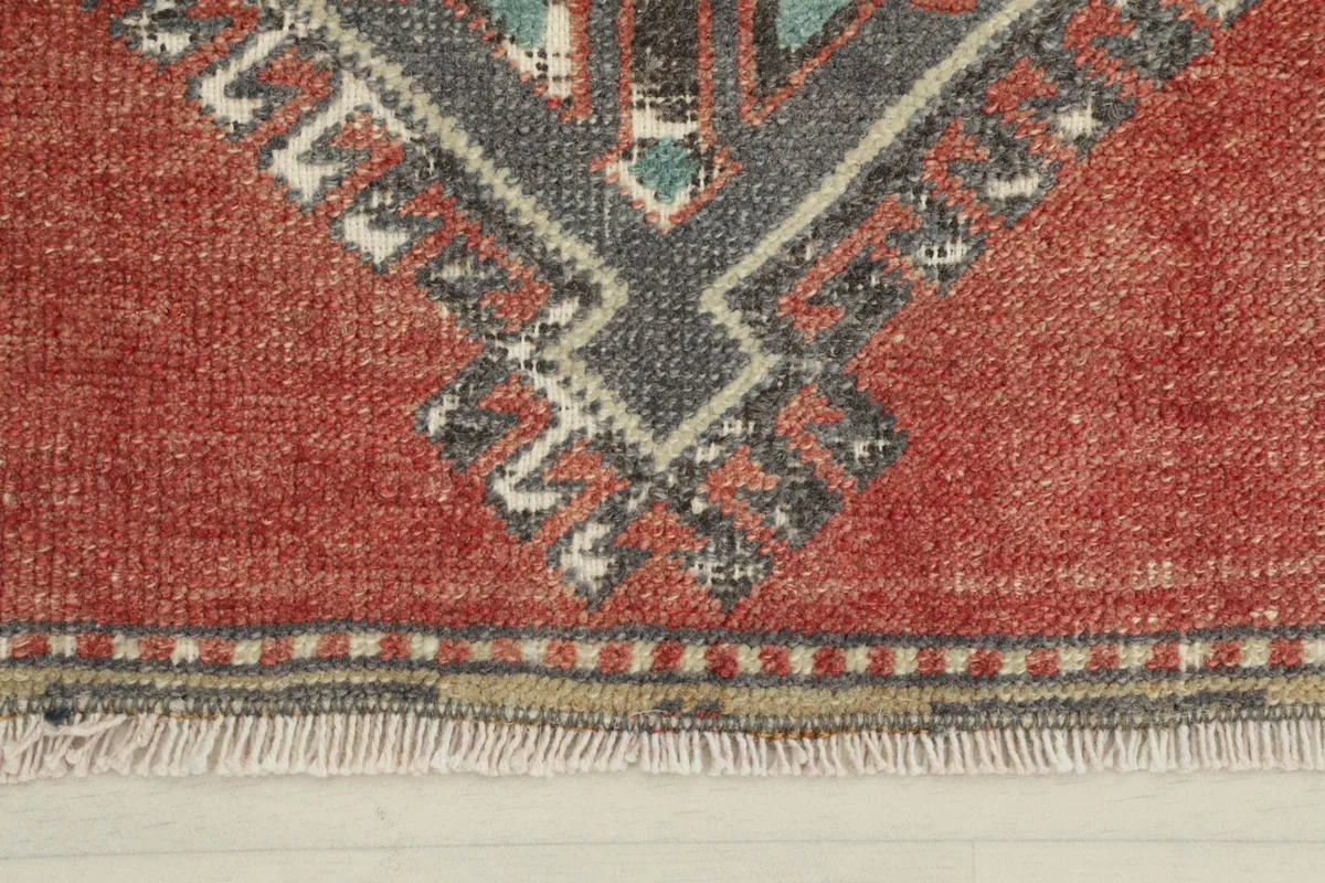 Close-up detail of the red field and the bottom fringe of the hand-knotted rug.