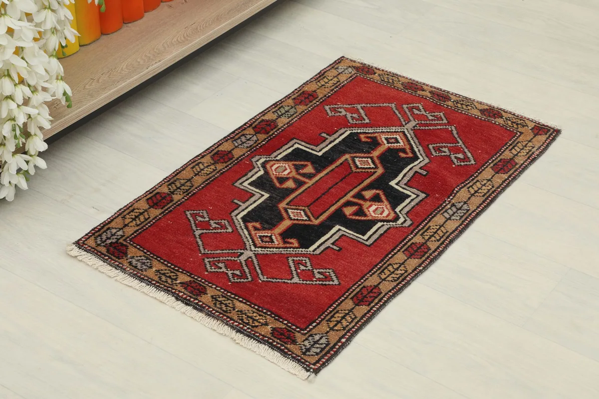 Angled view of the red vintage rug, showing its full design and texture.