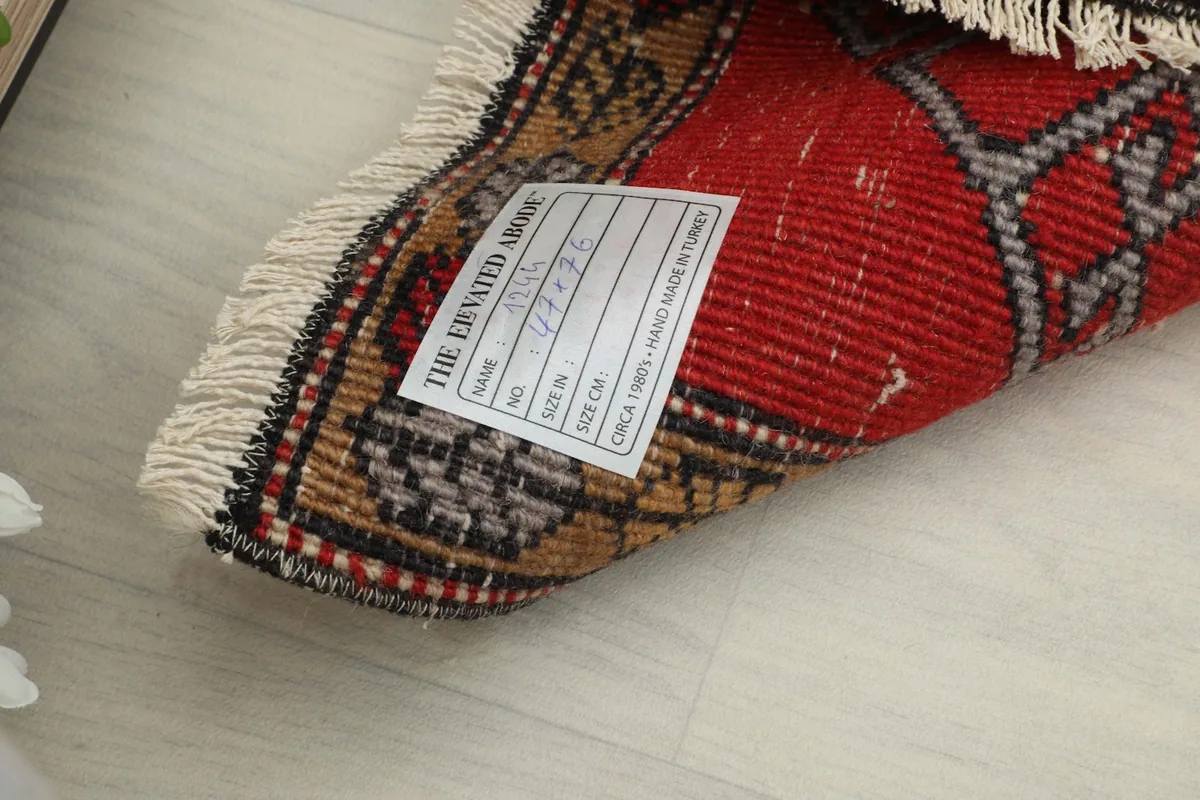 View of the rug's back and label, confirming its hand-knotted origin and size.