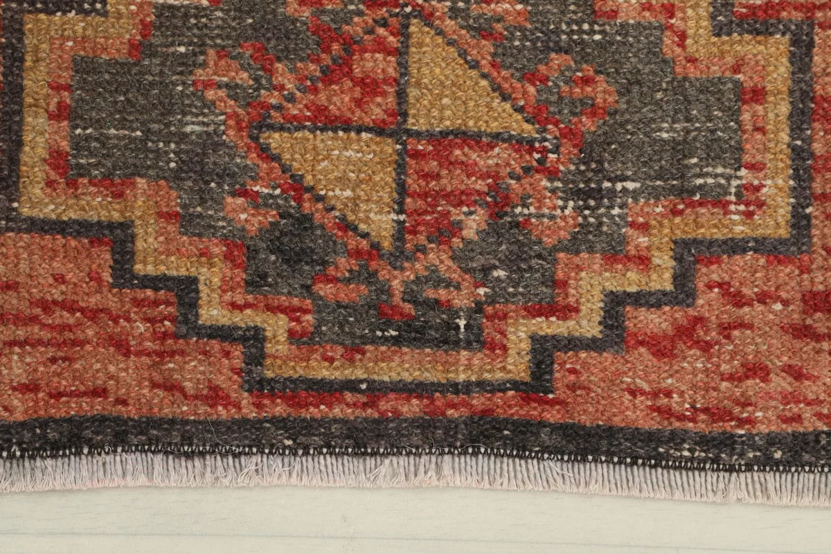 Close-up of the geometric motif and red, gold, charcoal colors in the vintage wool rug