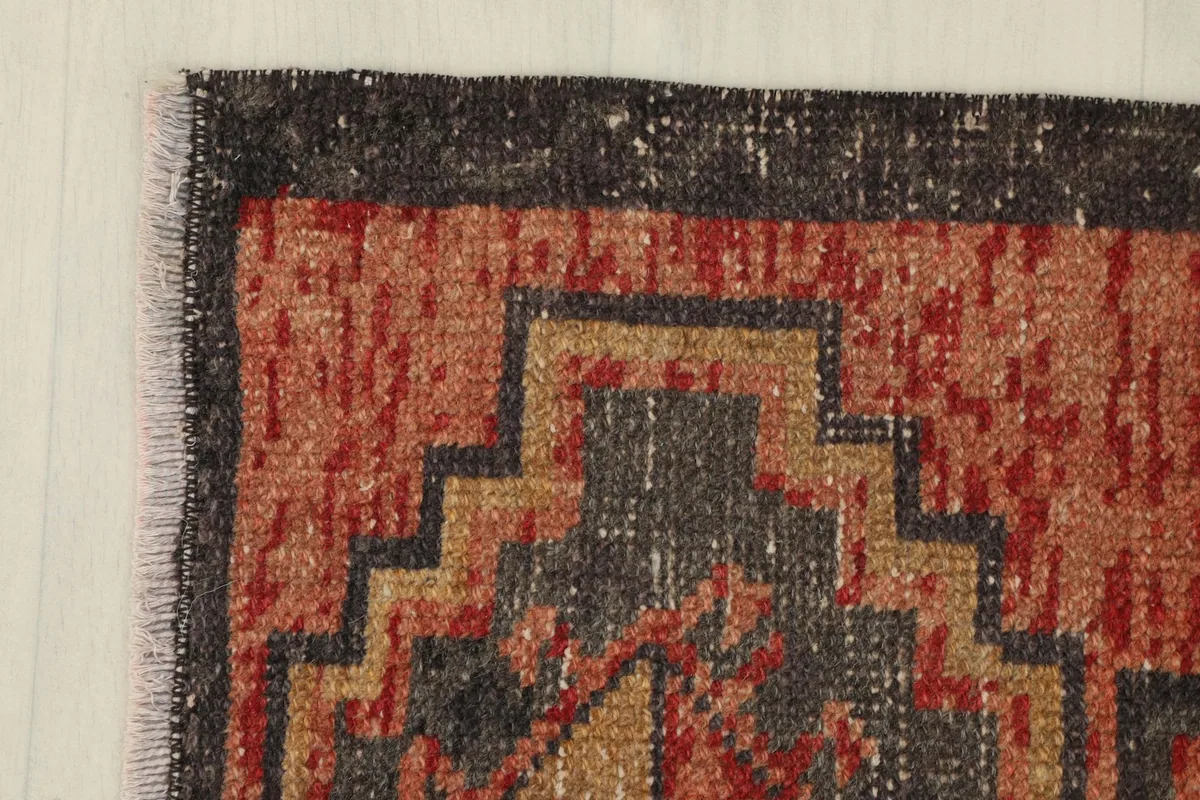 Corner view highlighting the charcoal border and fringe of the vintage Anatolian rug