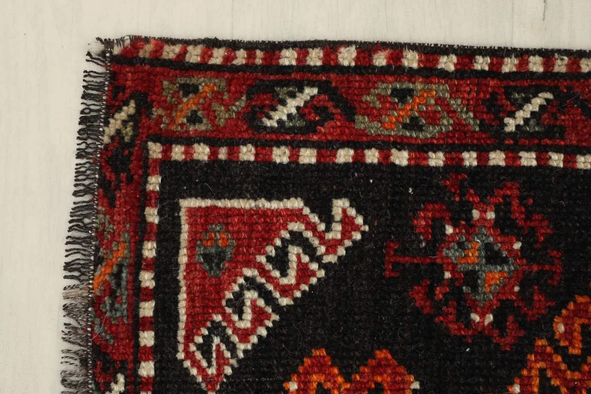 Detail of the rug's corner, showing the black border and red geometric elements