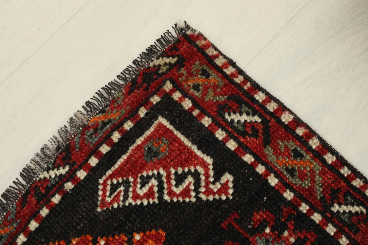 Corner view highlighting the intricate border design and fringe of the vintage rug