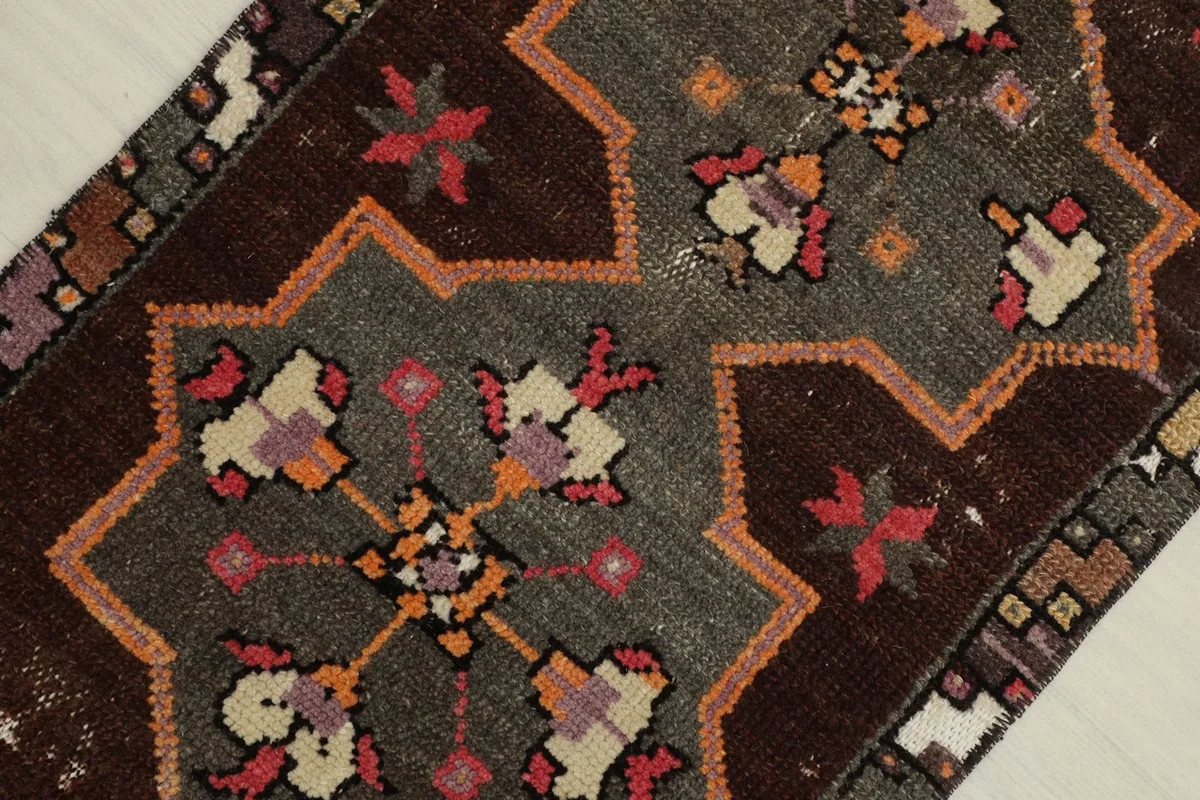 Detailed view of the central geometric medallion and surrounding tribal motifs in brown, gray, and orange.