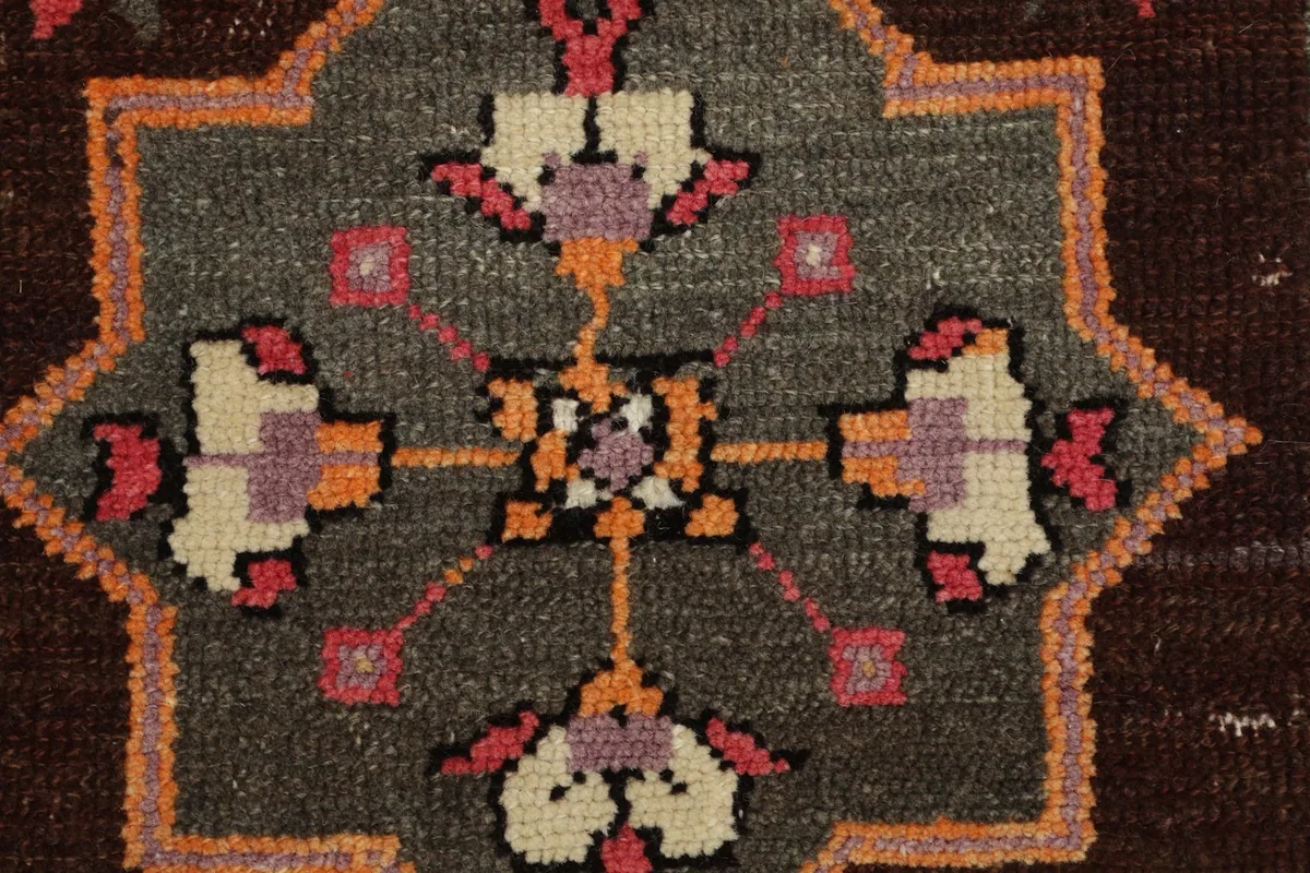 Top-down close-up of the central gray medallion with intricate rose, orange, and cream geometric patterns.
