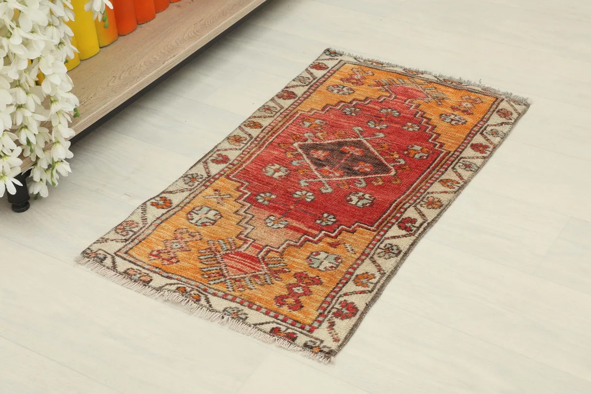 Angled view of the vintage doormat, showcasing its red and orange colors and patterns