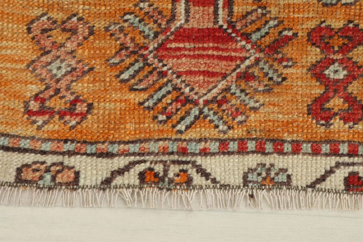 Close-up detail of the doormat's orange section, showing patterns and fringe