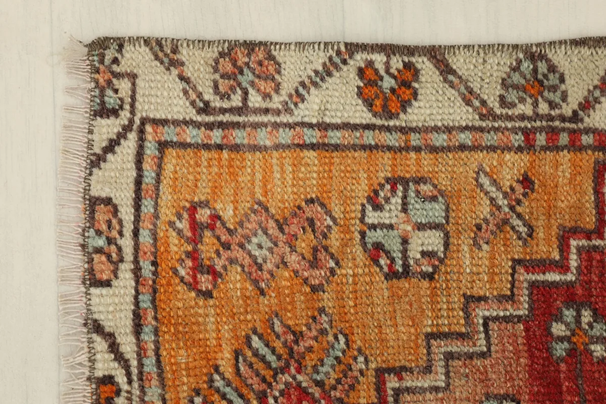 Corner detail showing the beige border with floral motifs and the orange field