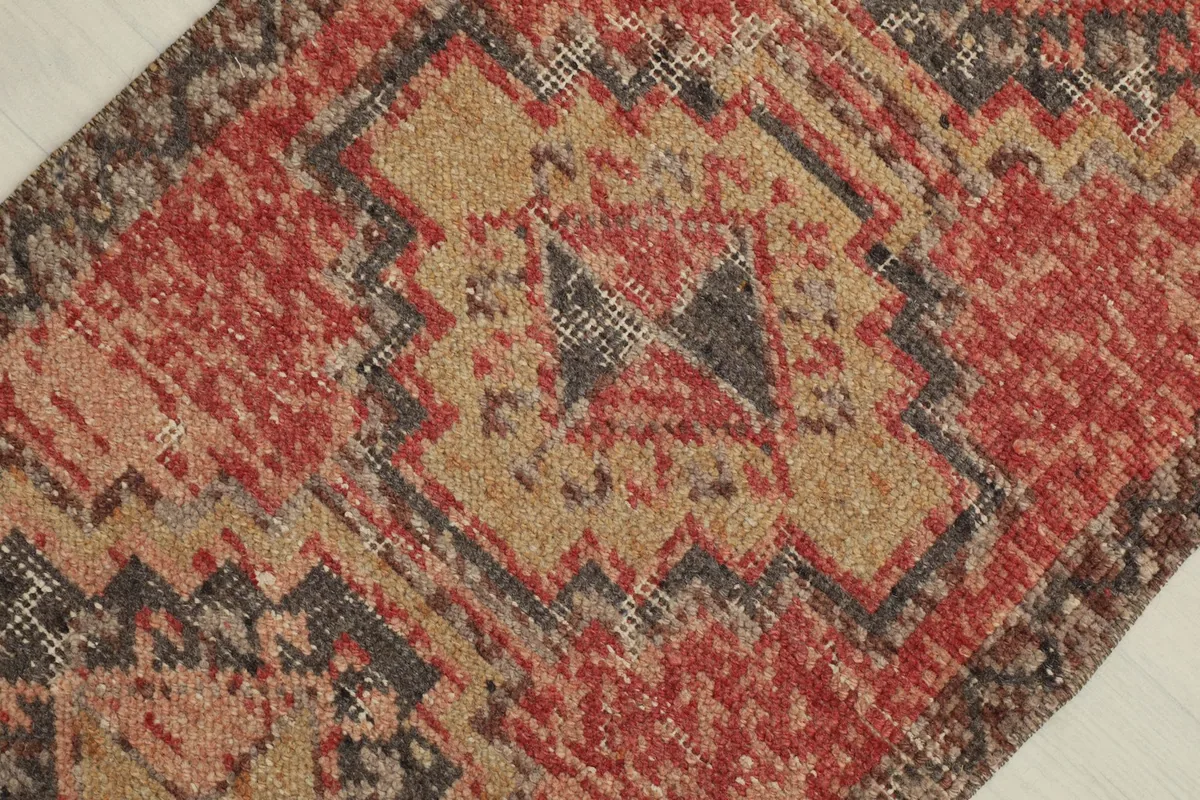 Detailed overhead view showing the distressed pile and intricate geometric design in rose, tan, and charcoal.