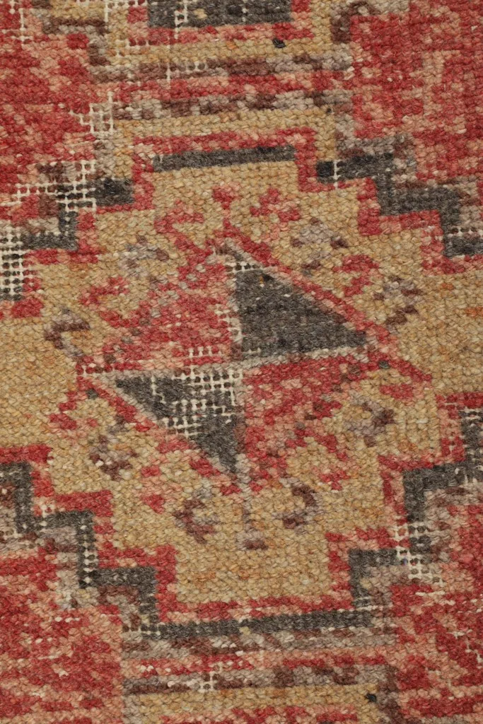 Macro view of the hand-knotted wool pile, revealing the natural wear and color variations within the patterns.
