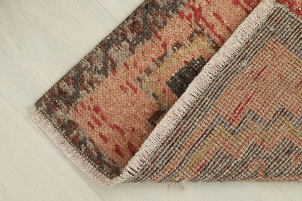 Rug partially folded, revealing the reverse side and the visible cotton foundation of the hand-knotted construction.