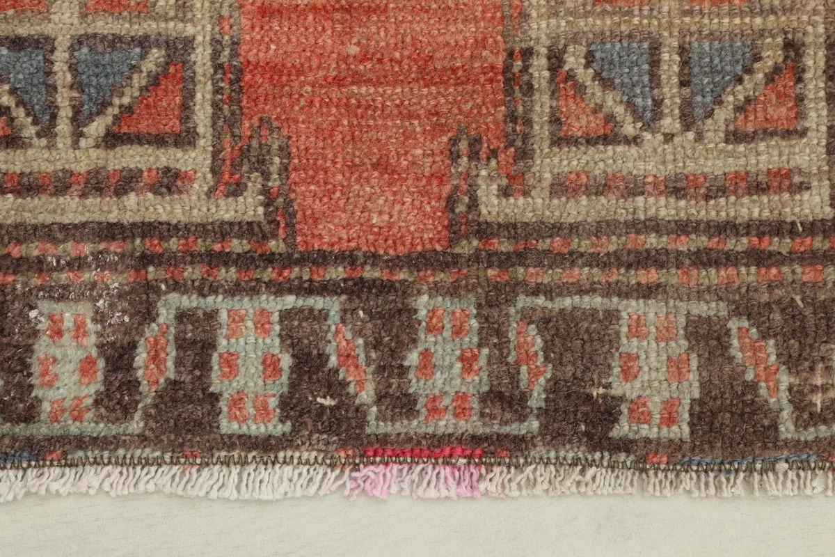 Close-up detail of the lower border and fringe of the rust and brown vintage rug.