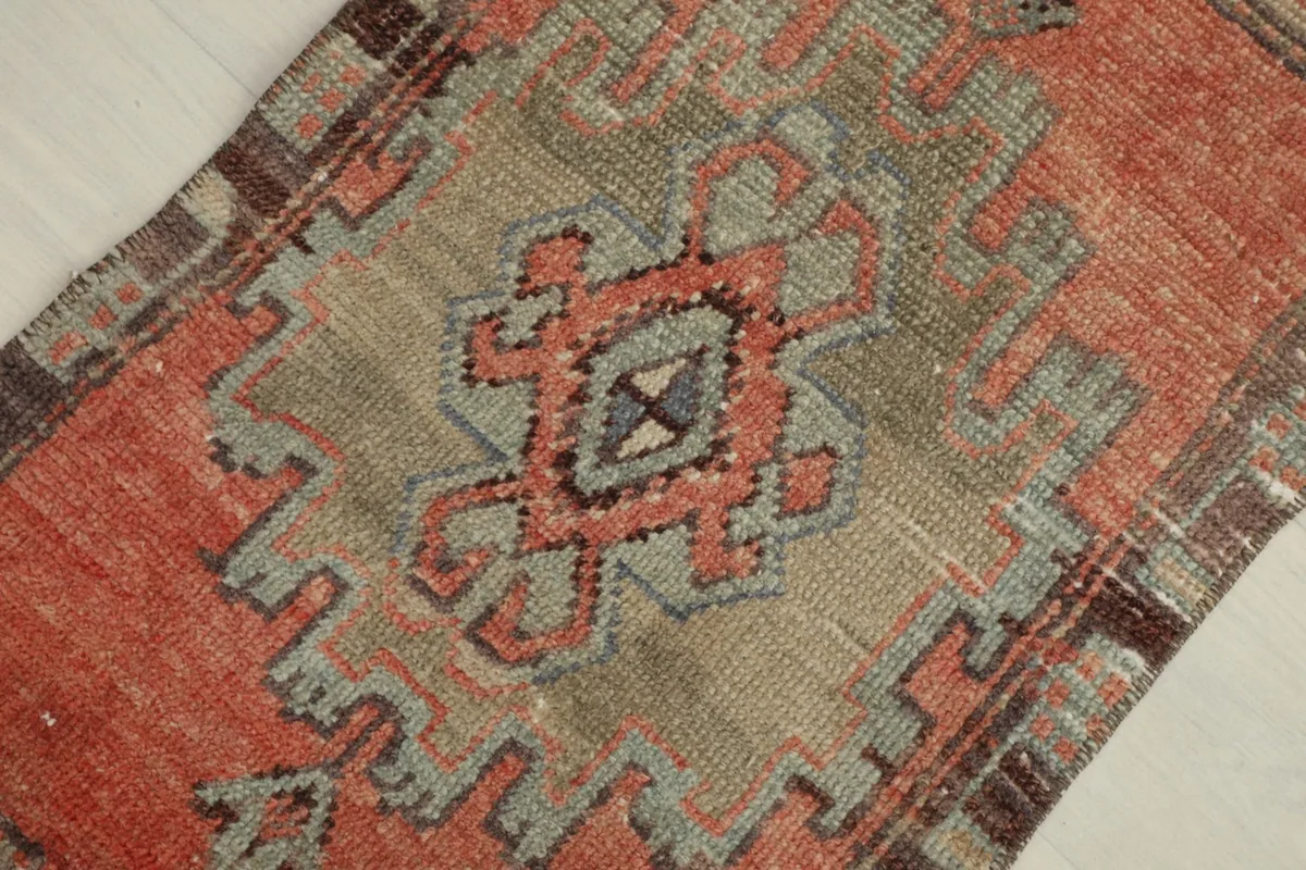 Close-up angled view of the central medallion and geometric patterns in rust, beige, and gray.