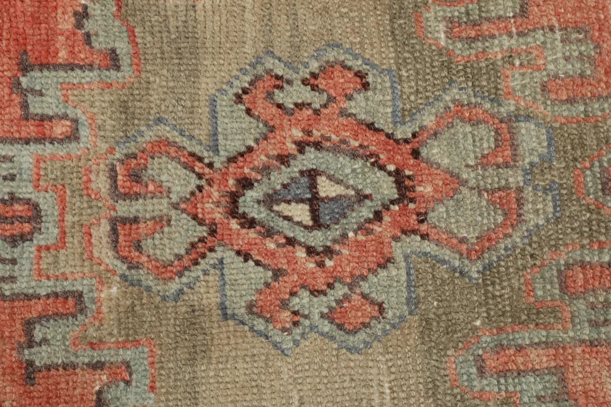 Overhead close-up of the central medallion motif with rust, beige, gray, and blue accents.