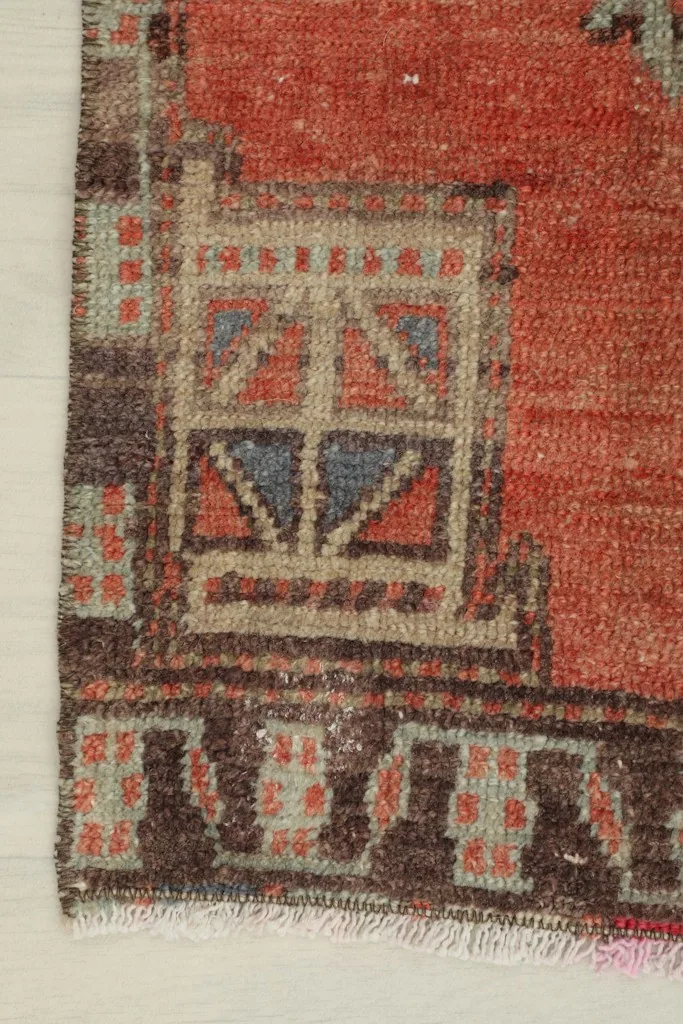 Detail of the corner showing geometric motifs and border in rust, brown, and beige tones.
