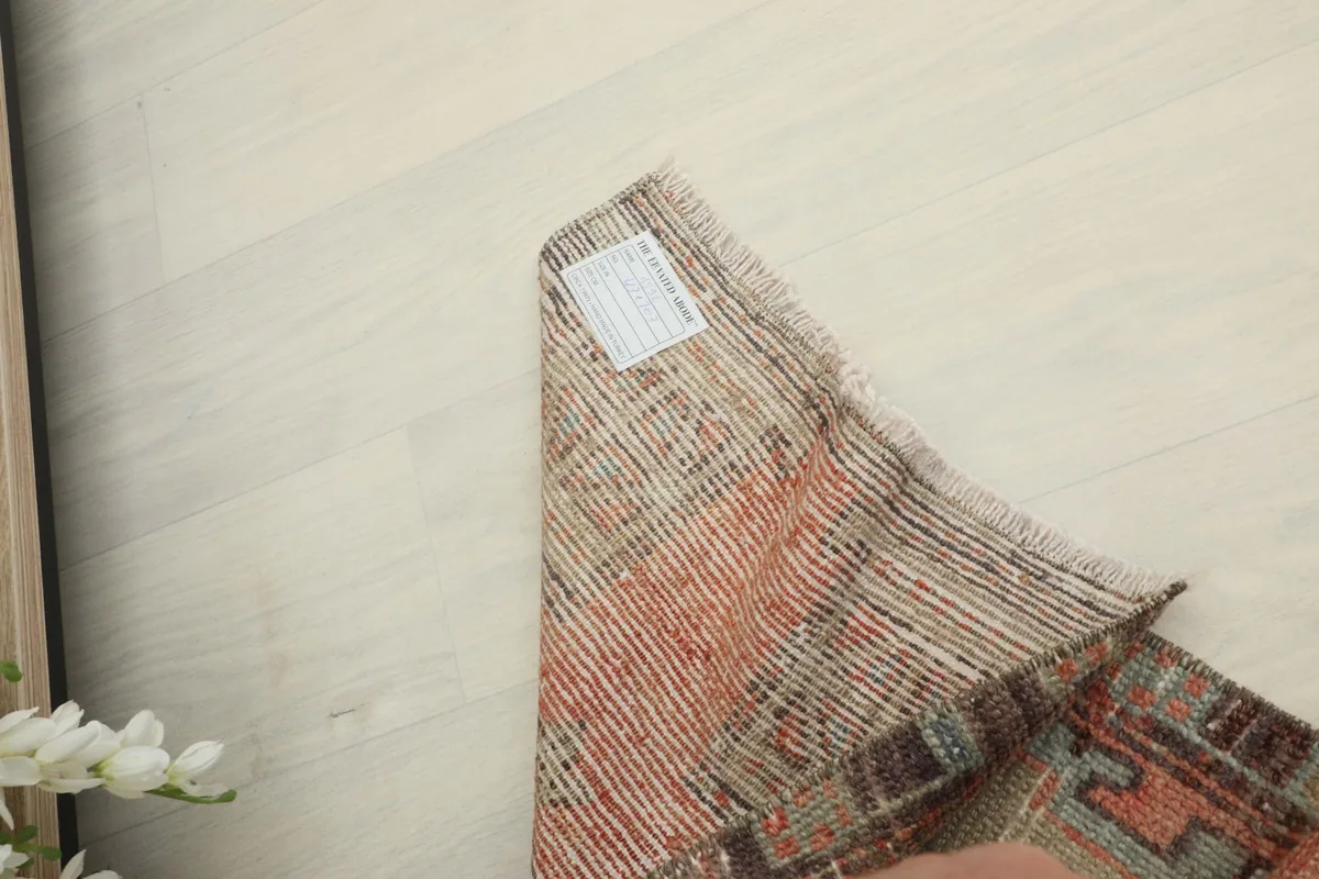 Corner of the rug folded back, displaying the woven structure of the cotton foundation.