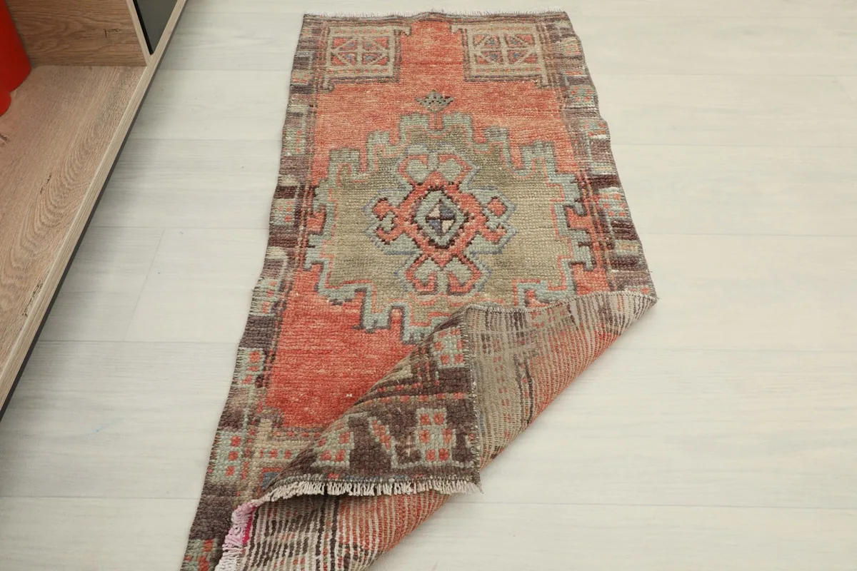 Rug partially folded, showing the pile side and the back of the vintage doormat.