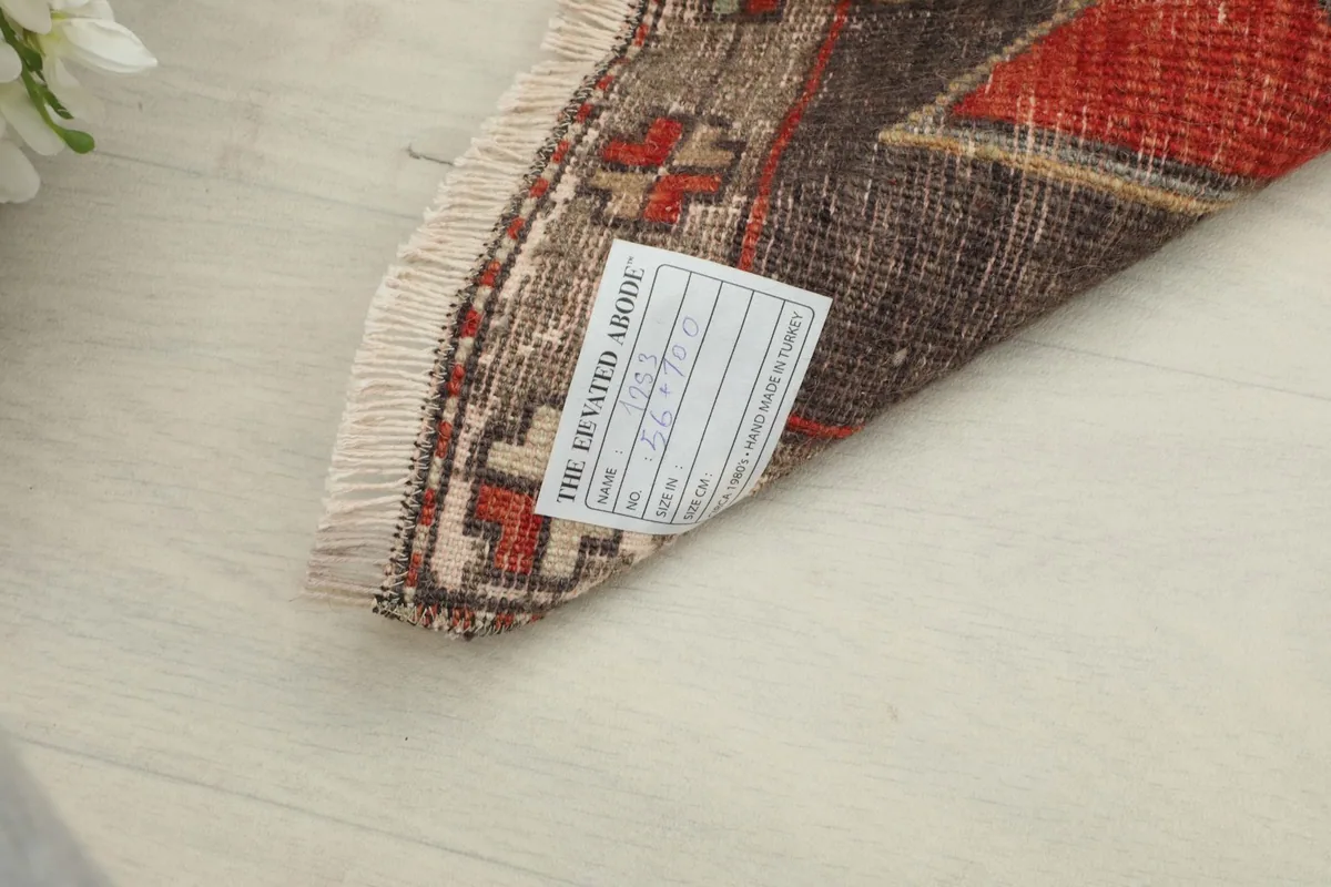 View of the back of the rug near the fringe, showing the cotton foundation and a product label.