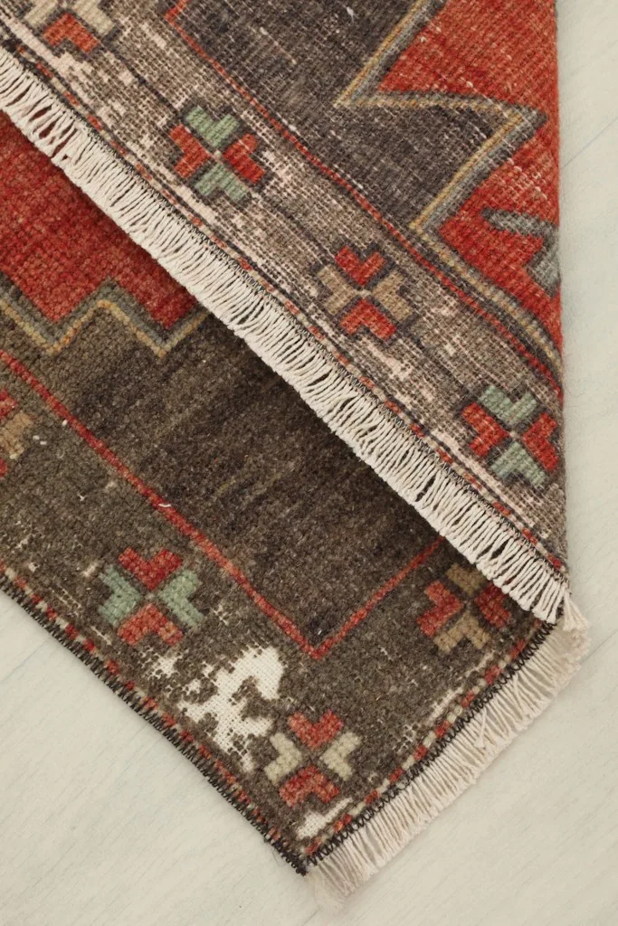 Folded corner of the rug, showcasing the thickness of the wool pile and the hand-knotted construction.
