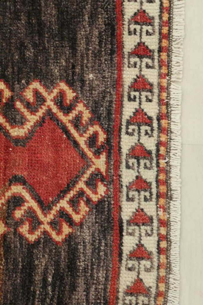 Close-up detail of the dark brown section and beige border with red and black geometric patterns.