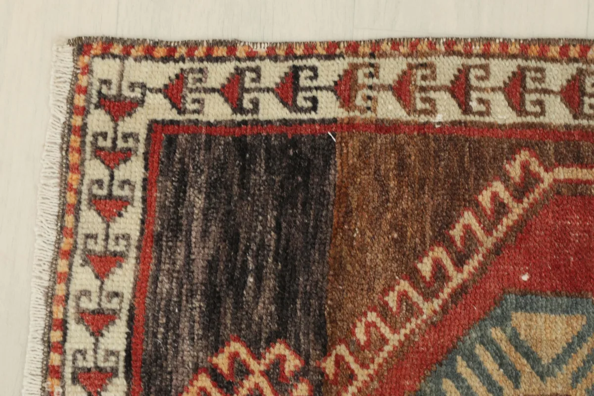 Close-up of the upper left corner showing the beige border and the dark brown section of the rug.