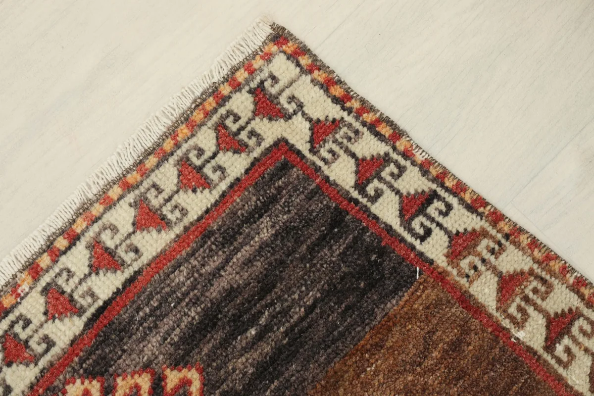 Close-up of the upper right corner of the rug, highlighting the beige border and dark section.