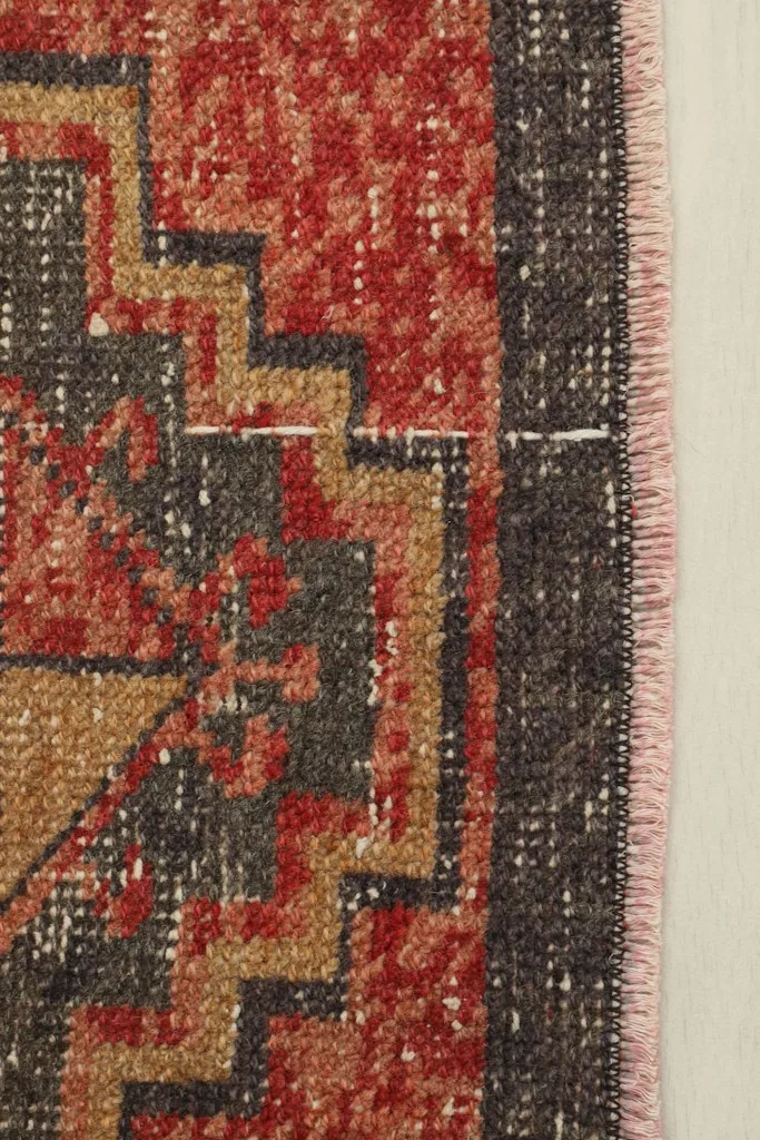 Close-up detail of the rug's border and a section of the geometric pattern, highlighting colors.