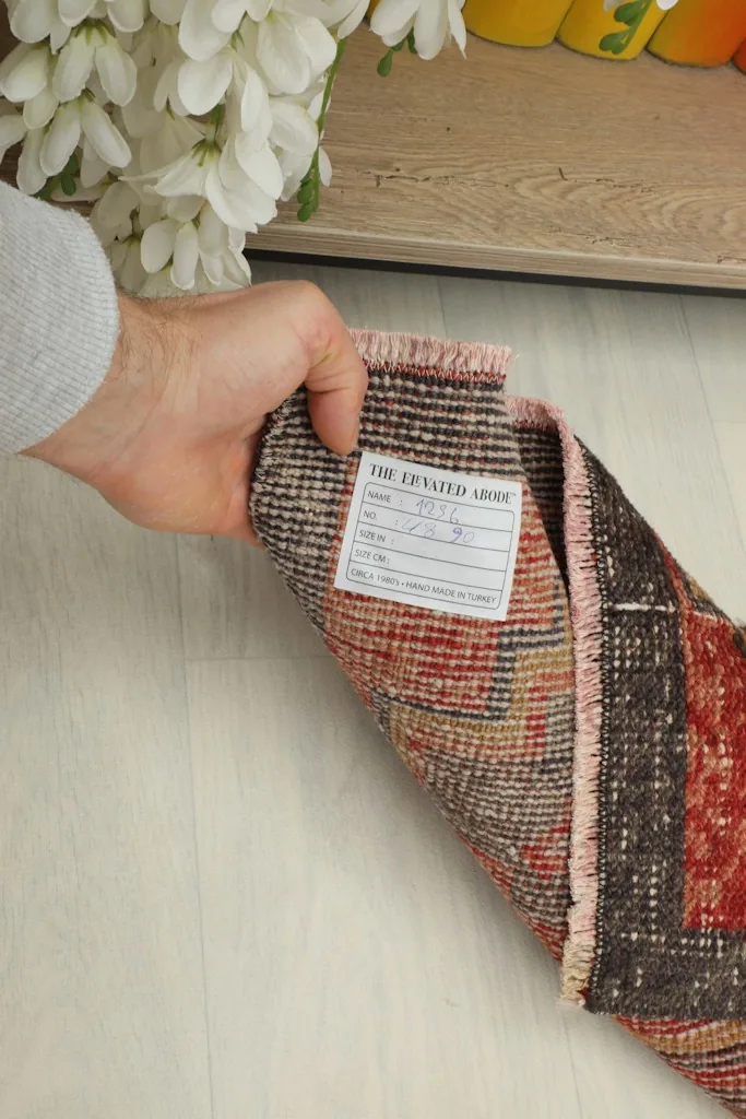 Hand holding a label on the back of the rug, showing the product information tag.