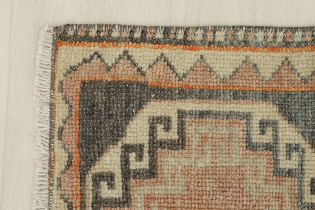 Top corner detail of the rug, focusing on the geometric patterns and the condition of the edges
