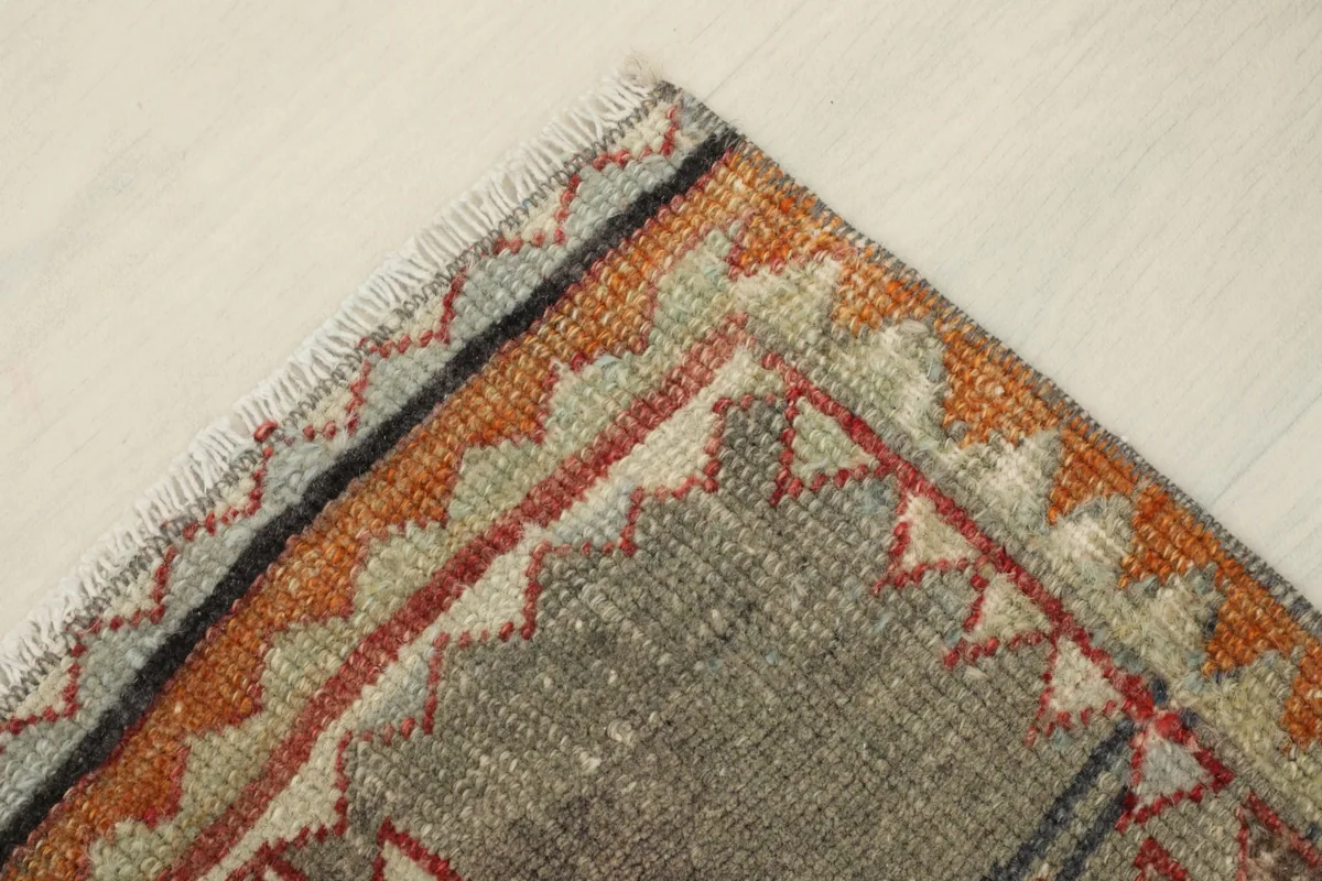 Angled view focusing on a corner of the rug, illustrating the varied color tones and hand-knotted texture.