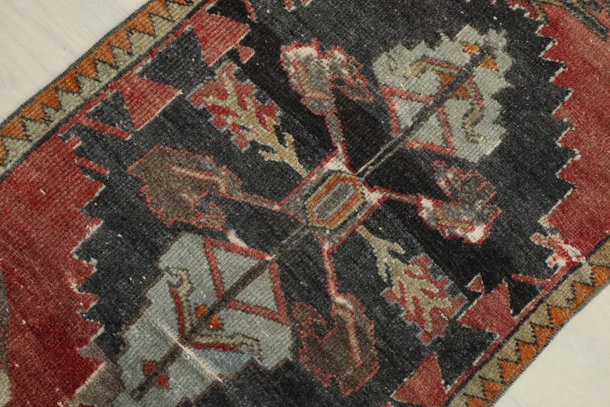 Detailed view of the central charcoal field with intricate tribal motifs in rust, gray, and blue tones.